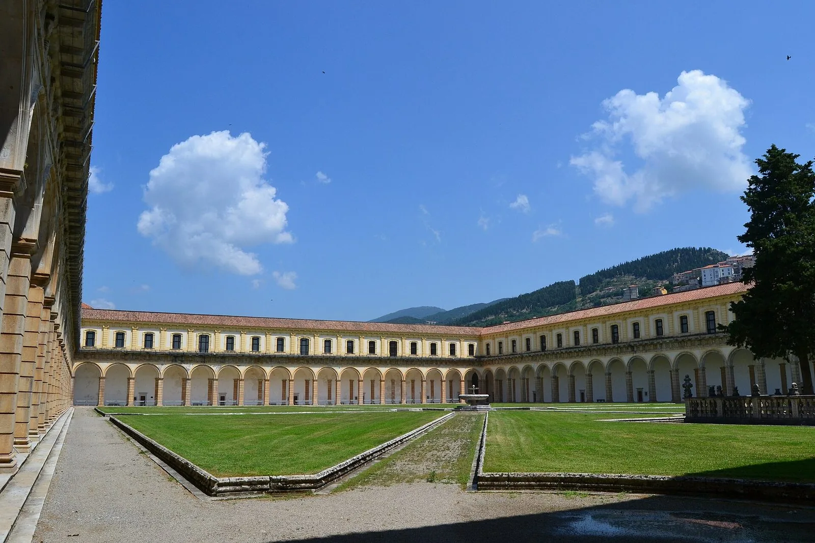 Il chiostro grande della Certosa di Padula con il prato centrale, il porticato ad arcate su due ordini e le montagne sullo sfondo