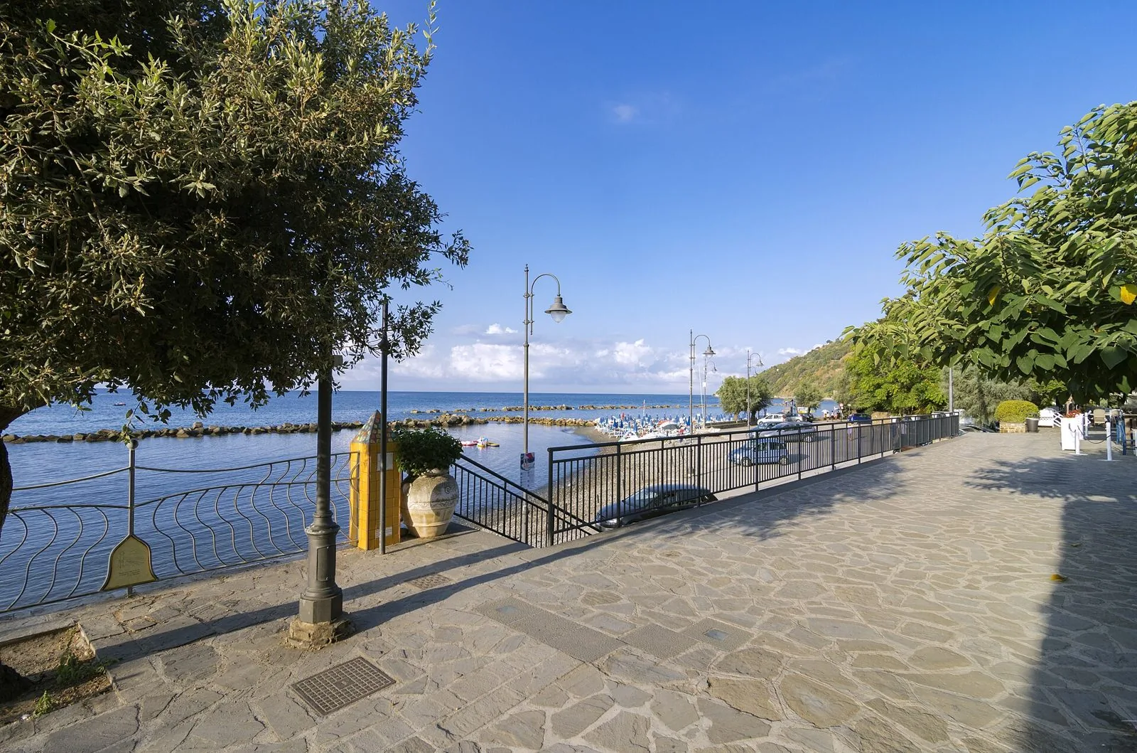 Il lungomare lastricato di Pioppi con alberi, lampioni e la spiaggia affacciata sul mare cilentano